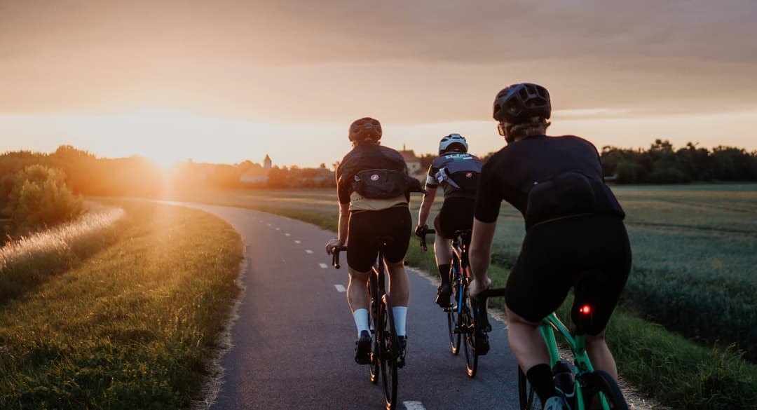Cyclists riding into the sunset in a group